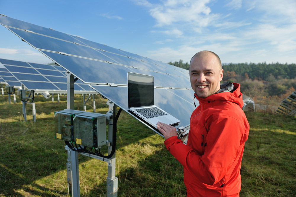 business man  engineer using laptop at solar panels plant eco energy field  in background